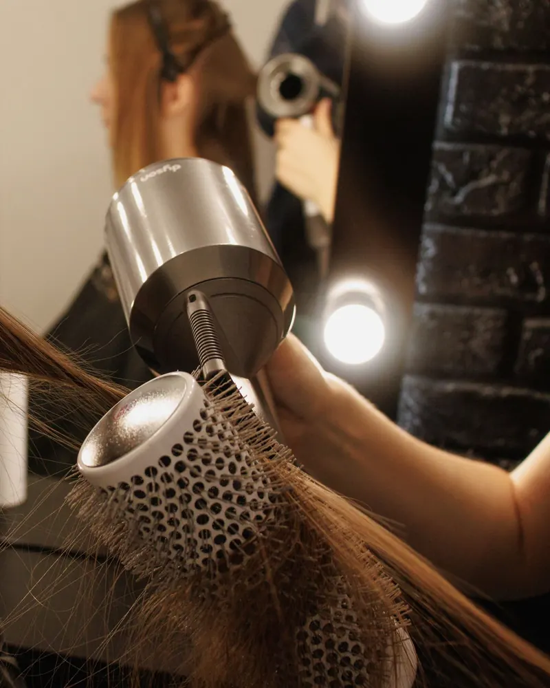 Estilista secando cabello largo con cepillo